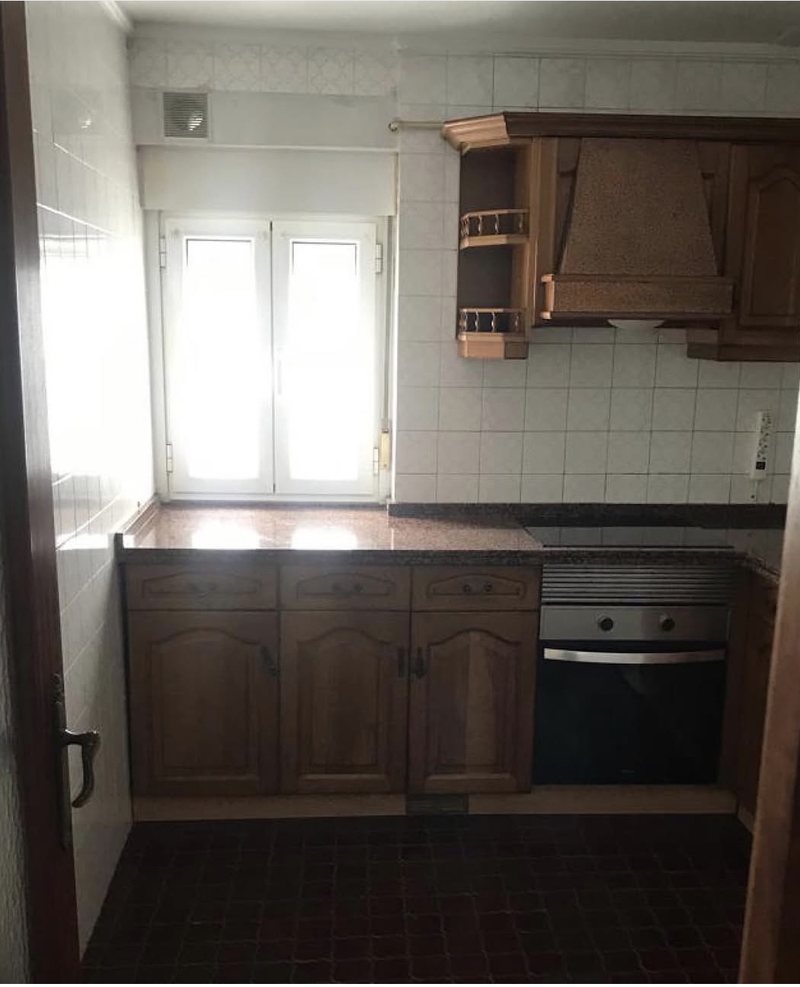 Cocina vista hacia la ventana antes del home staging: muebles de madera oscura y suelo marrón