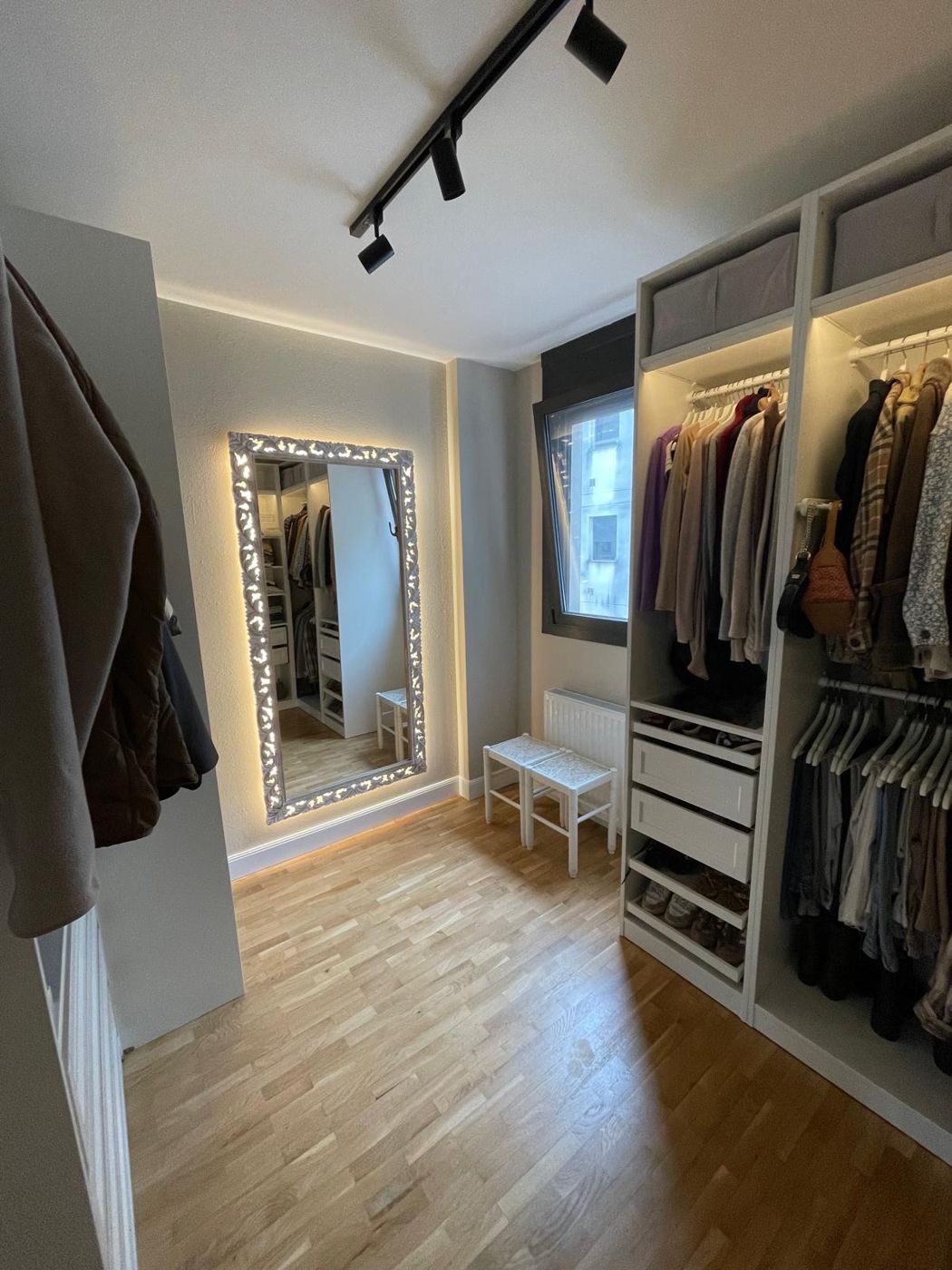 Vestidor terminado con armarios abiertos, espejo iluminado y focos en el techo